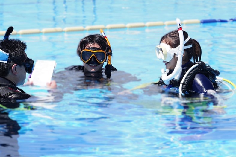 ダイビング講習でインストラクターと少人数で水面に浮かびながら説明を受けている様子。初心者でも安心して参加できる環境